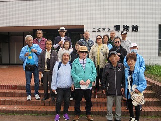 三笠市博物館の入り口で記念写真の写真です。17名が階段のまえではいポーズ。事前にマスクをとり撮影しました。